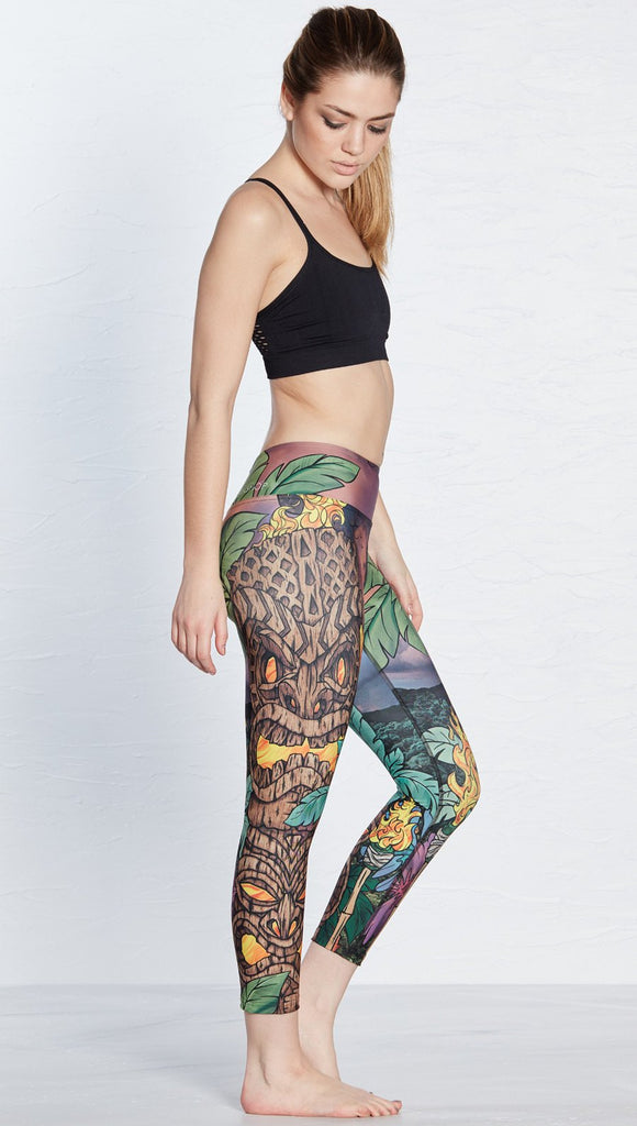 right side view of model wearing tiki torch themed printed capri leggings