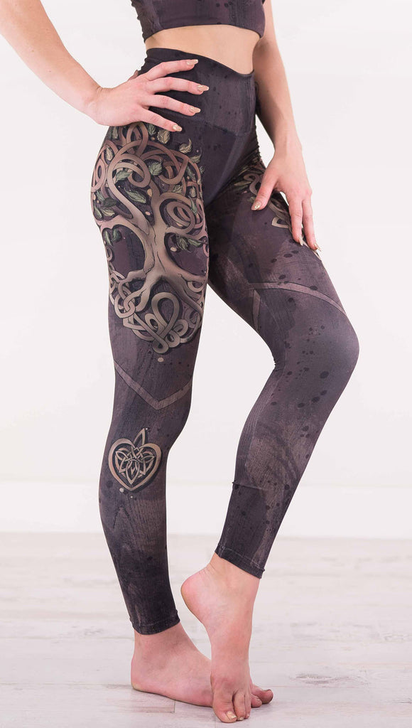 Right view of model wearing the Tree of Life athleisure leggings in a brown wood grain print with a tree across the side