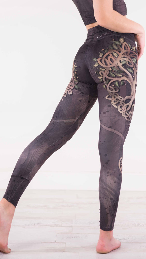 Enhanced back view of model wearing the Tree of Life athleisure leggings in a brown wood grain print with a tree on each side
