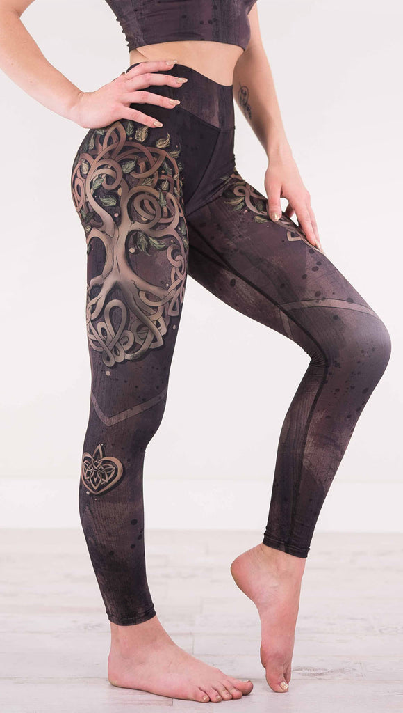Enhanced right view of model wearing the Tree of Life triathlon leggings in a brown wood grain print with a tree on the side