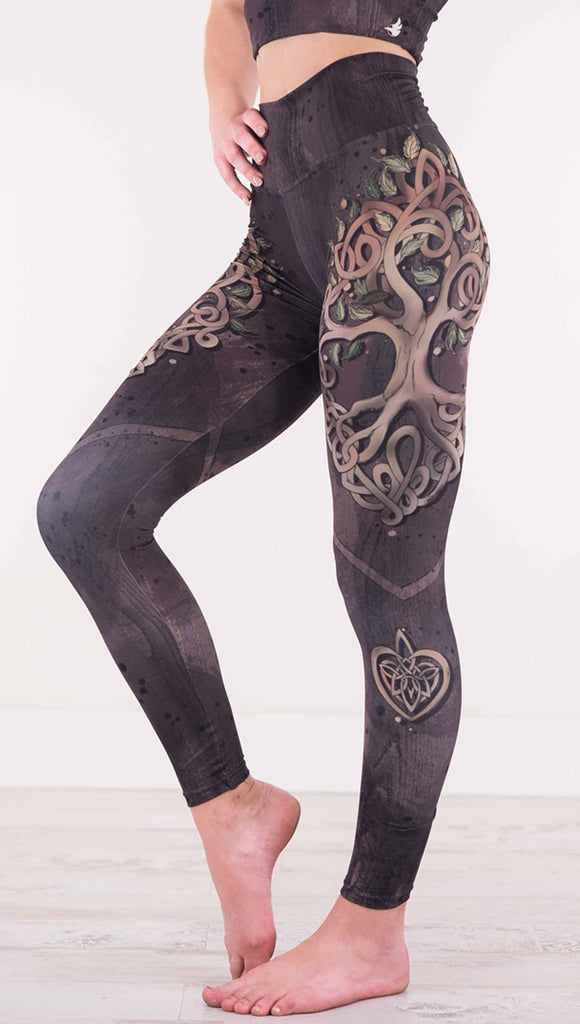 Enhanced left view of model wearing the Tree of Life athleisure leggings in a brown wood grain print with a tree across the  side