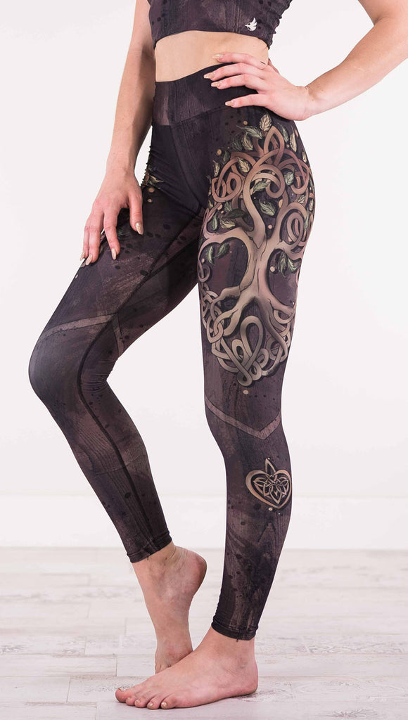 Enhanced left view of model wearing the Tree of Life triathlon leggings in a brown wood grain print with a tree on the side