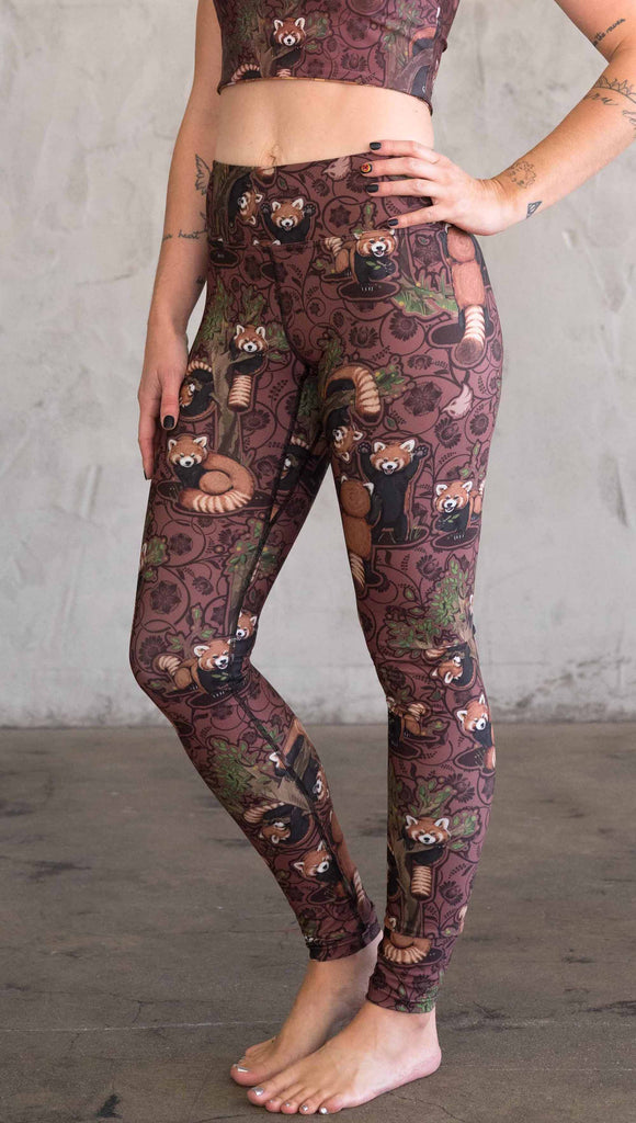 Side view of WEKSHOP red panda leggings in triathlon fabric. The artwork is dark red base with clusters of cute little red pandas playing on trees.