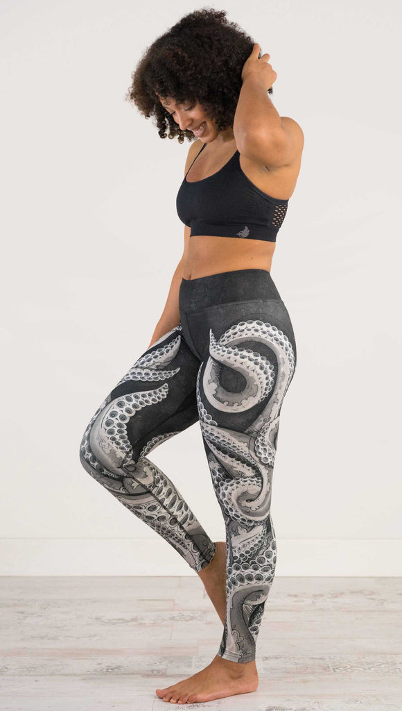 Full Body, side view of model wearing WEKSHOP Tentacles Full Length Triathlon Leggings. The artwork is monochrome black and white and features large tentacles wrapping around the legs from the bottom reaching upward.