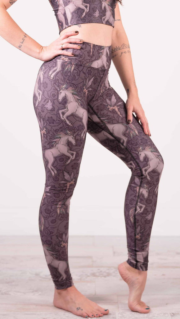 Model wearing WERKSHOP Full Length Triathlon leggings with Original Unicorn artwork. The unicorns have soft rainbow colored hair and a small pixie friend over a purple background.