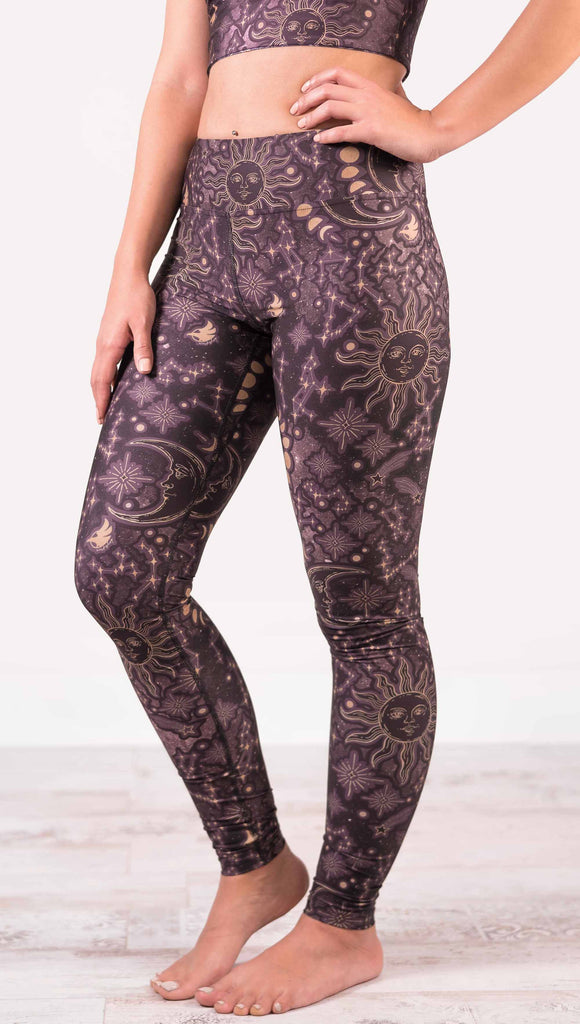 model wearing WERKSHOP Zodiac Full Length Triathlon Leggings. The zodiac themed artwork shows a hand-drawn sun and moon with the moon phases, shooting stars and all 12 zodiac constellations in gold over a dark purple background. Triathlon leggings do not have pockets.