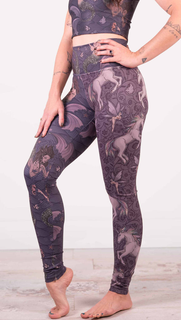 Model wearing WERKSHOP Mermaid and Unicorn Mashup Athleisure Leggings. The leggings feature mermaid artwork on the wearers right leg with a dark blue background and unicorns over a purple background on the wearer's left leg.