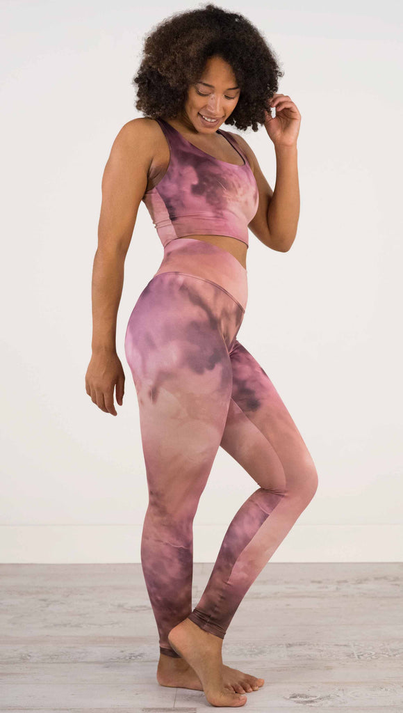 Full body front view of model wearing WERKSHOP Rose Quartz Athleisure Leggings. The leggings are printed with a warm rose/mauve and peachy watercolor effect with our eagle logo printed on the wearers outside left calf.