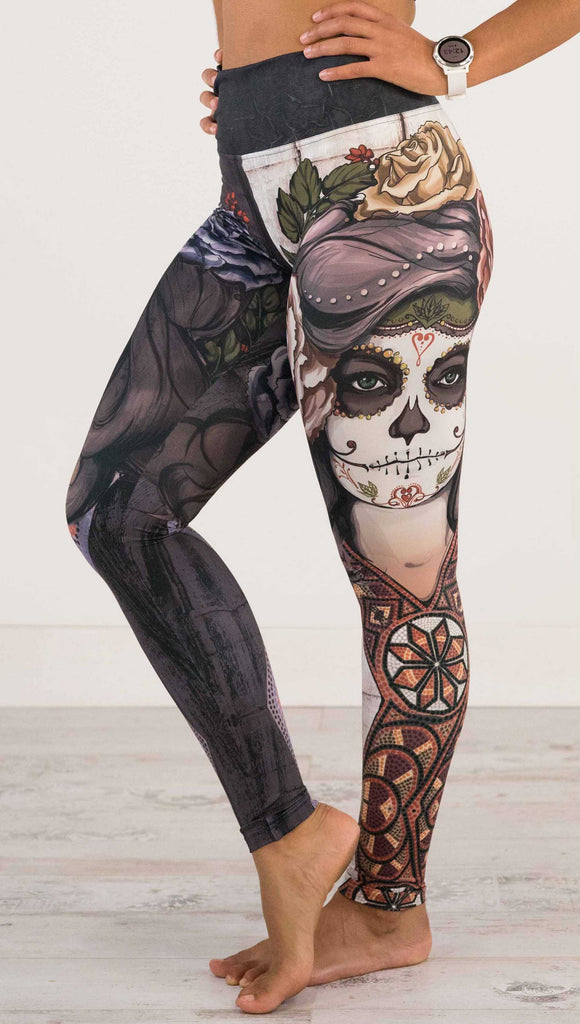 Waist down front view of model wearing WERKSHOP Sugar Mashup Athleisure Leggings. The leggings are printed with original sugarskull themed artwork. The wearers left leg features "Remix", a romantic lighter version of the artwork with mauve roses in her hair. The other leg is printed with Dark Sugar, an edgier version of the same artwork with blue flowers in her hair. 