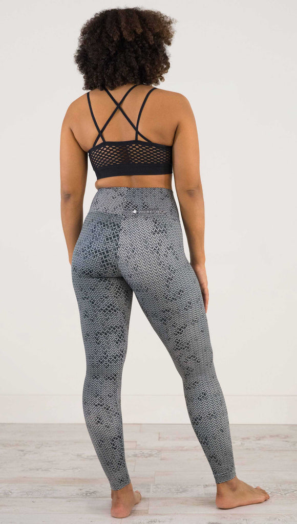 Full body back view of model wearing WERKSHOP Chainmaille Athleisure Leggings. The leggings are printed with a photo-real image of actual chainmaille. Perfect for a Renaissance Festival.