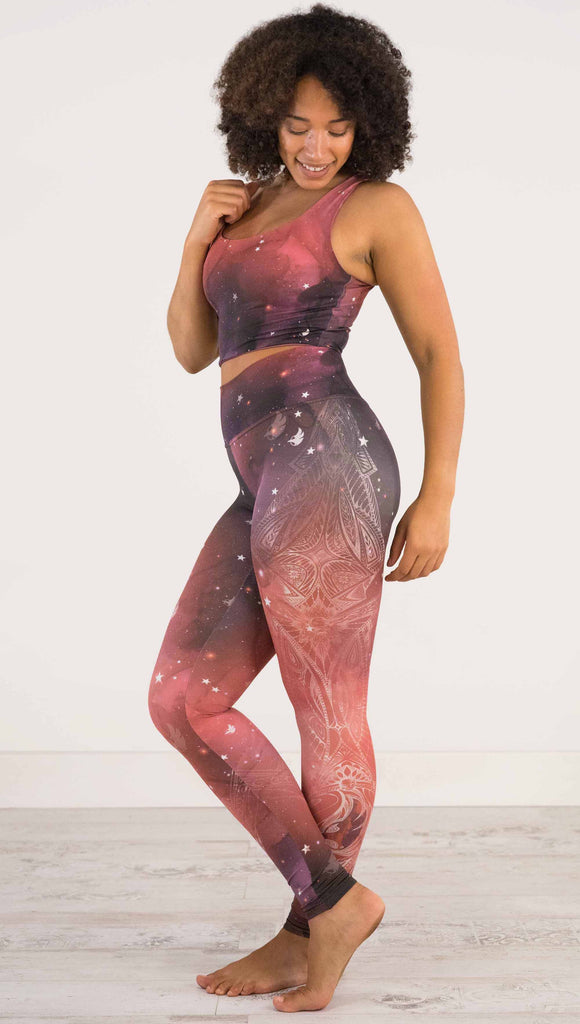 full body side view of model wearing a red, orange and purple galaxy themed athleisure leggings with white henna inspired art running along the right side of the leg