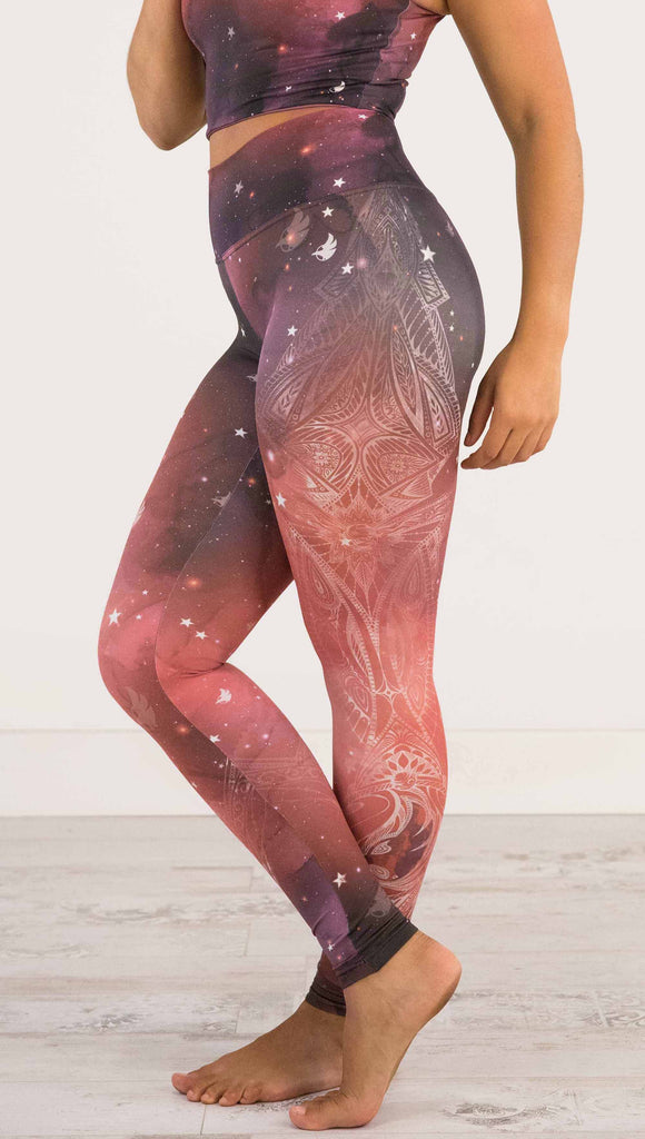 waist down view of model wearing a red, orange and purple galaxy themed athleisure leggings with white henna inspired art running along the right side of the leg