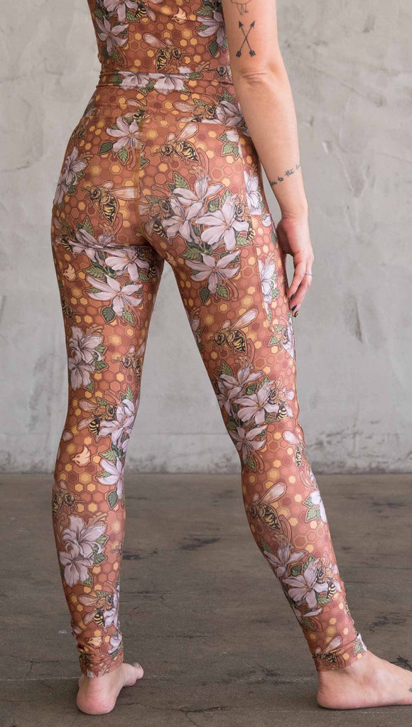 Back view of model wearing ultra lightweight "featherlight" leggings with clusters of honeybees and flowers.  