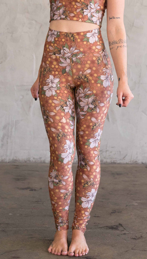 Front view of model wearing ultra lightweight "featherlight" leggings with clusters of honeybees and flowers.