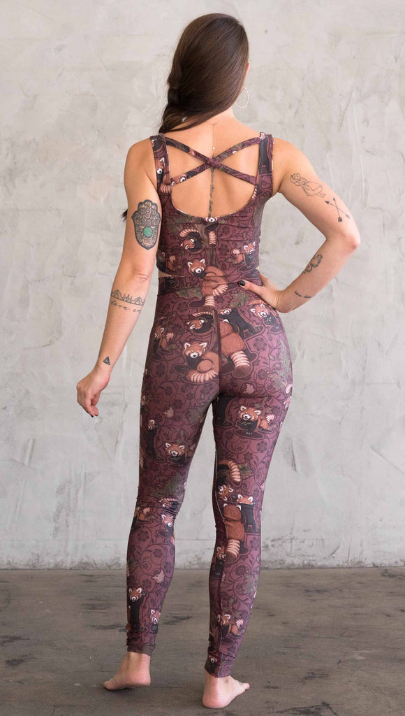 Back view of model wearing WERKSHOP Red Panda Leggings. The artwork is dark red with clusters of cute red pandas playing on trees. The leggings have phone pockets on both legs.