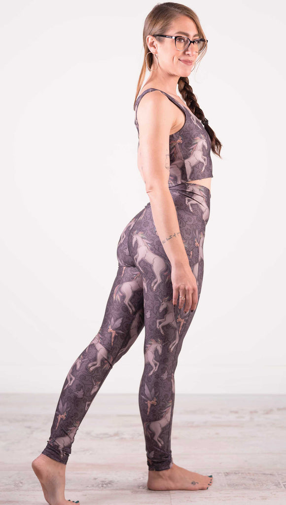 Side view of model wearing WERKSHOP featherlight featherlight leggings with Original Unicorn artwork. The unicorns have soft rainbow colored hair and a small pixie friend over a purple background. The leggings have large pockets on each hip large enough to hold a phone.