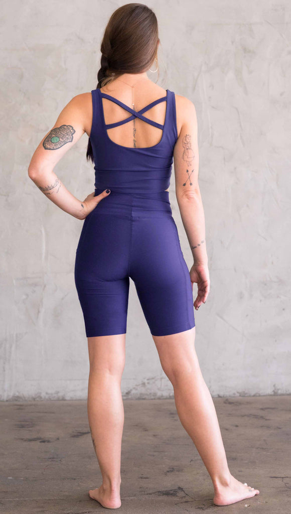 Model wearing WERKSHOP bicycle length shorts in featherlight fabric. Navy color with side cell phone pockets and a small eagle logo on the wearers left side