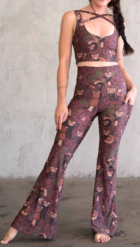 Front view of WEKSHOP red panda leggings in ultra lightweight featherlight fabric. The artwork is dark red base with clusters of cute little red pandas playing on trees and the bottoms have a large phone pocket on each leg.