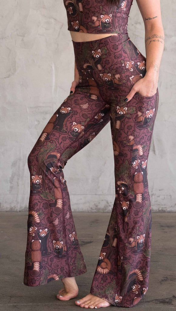 Side view of WEKSHOP red panda leggings in ultra lightweight featherlight fabric. The artwork is dark red base with clusters of cute little red pandas playing on trees and the bottoms have a large phone pocket on each leg.