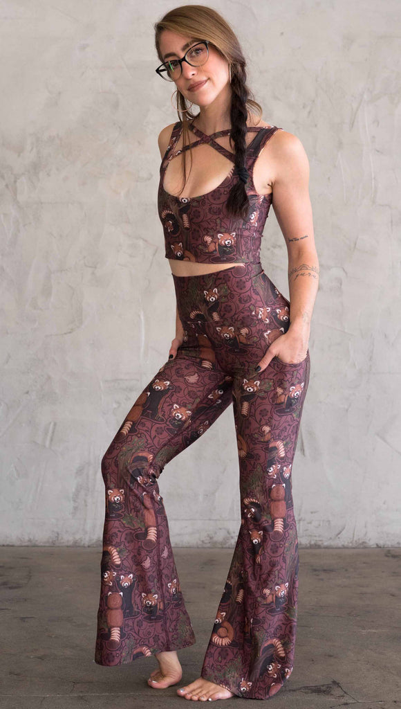 full body view of WEKSHOP red panda leggings in ultra lightweight featherlight fabric. The artwork is dark red base with clusters of cute little red pandas playing on trees and the bottoms have a large phone pocket on each leg.