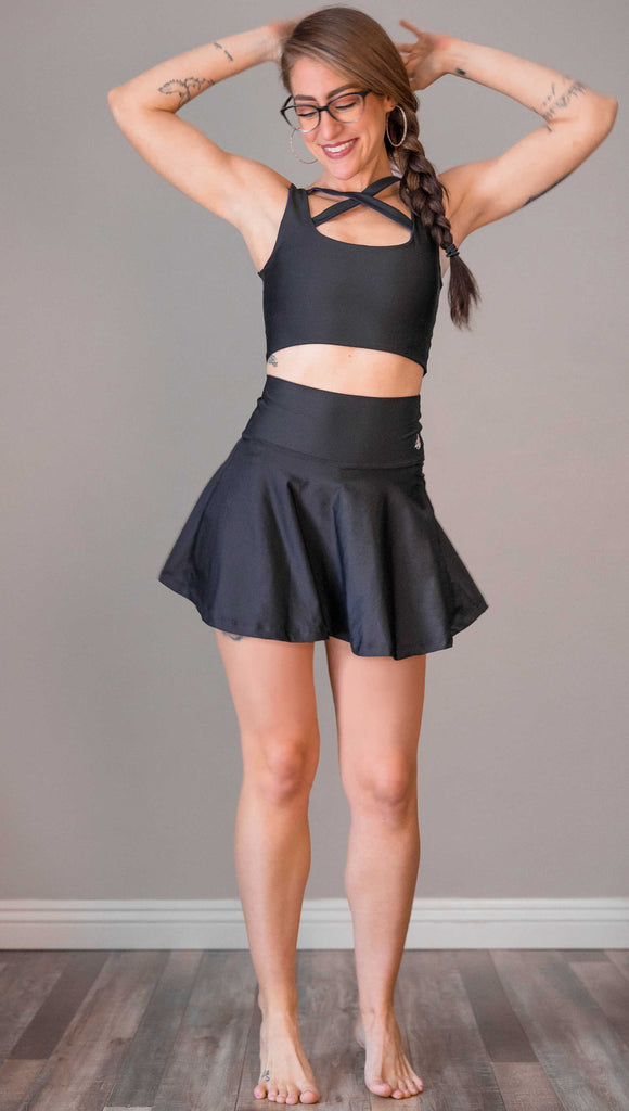 Full body view of model wearing WERKSHOP Tennis Skirt. In solid black color