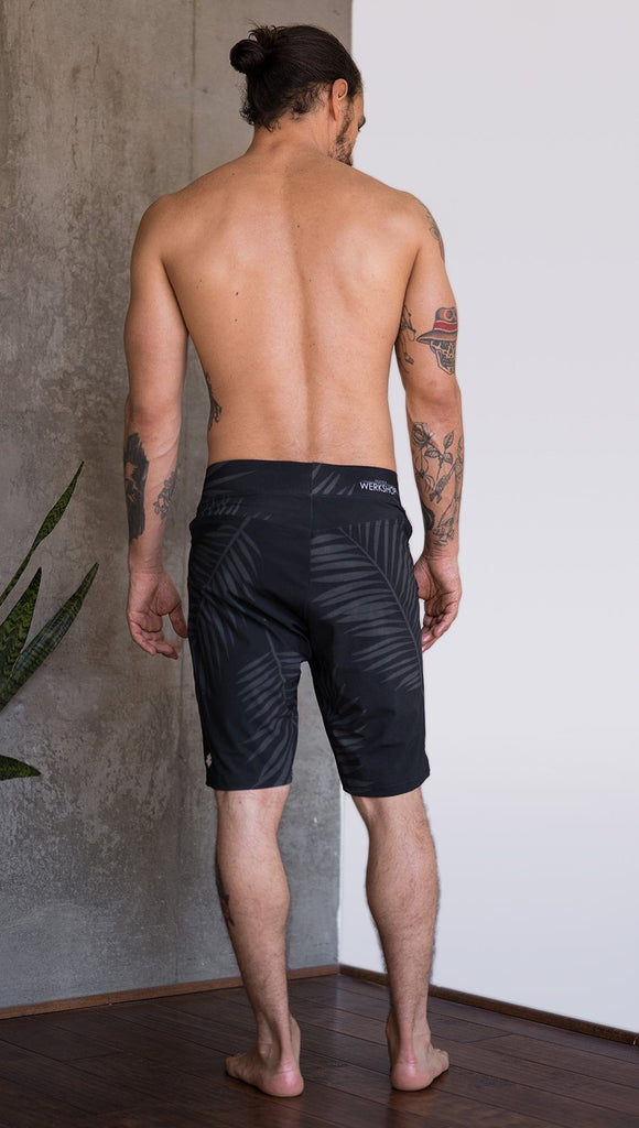 back view of model wearing tropical palm fronds printed mens performance shorts