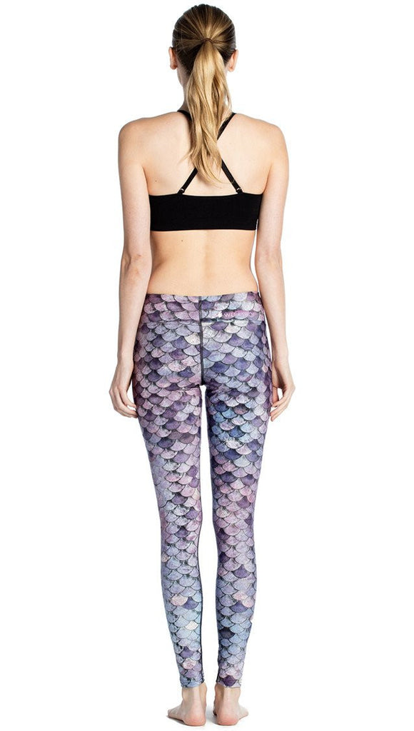 back view of model wearing purple mermaid scale themed printed full length leggings