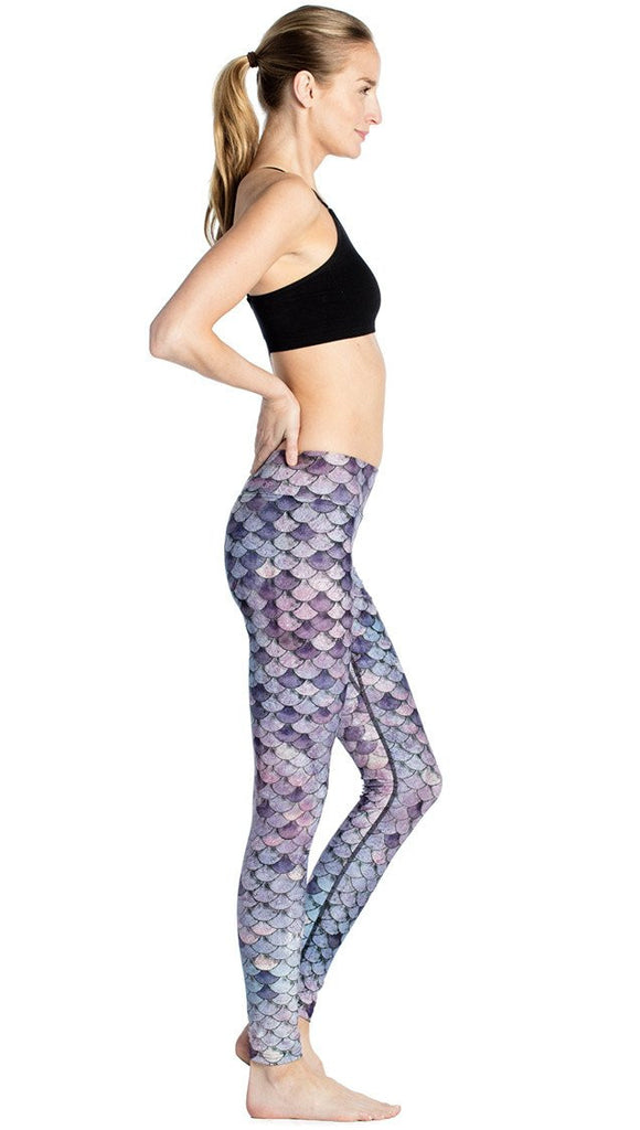 right side view of model wearing purple mermaid scale themed printed full length leggings