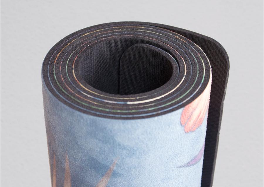 closeup view of rolled yoga mat with tropical floral design and blue background