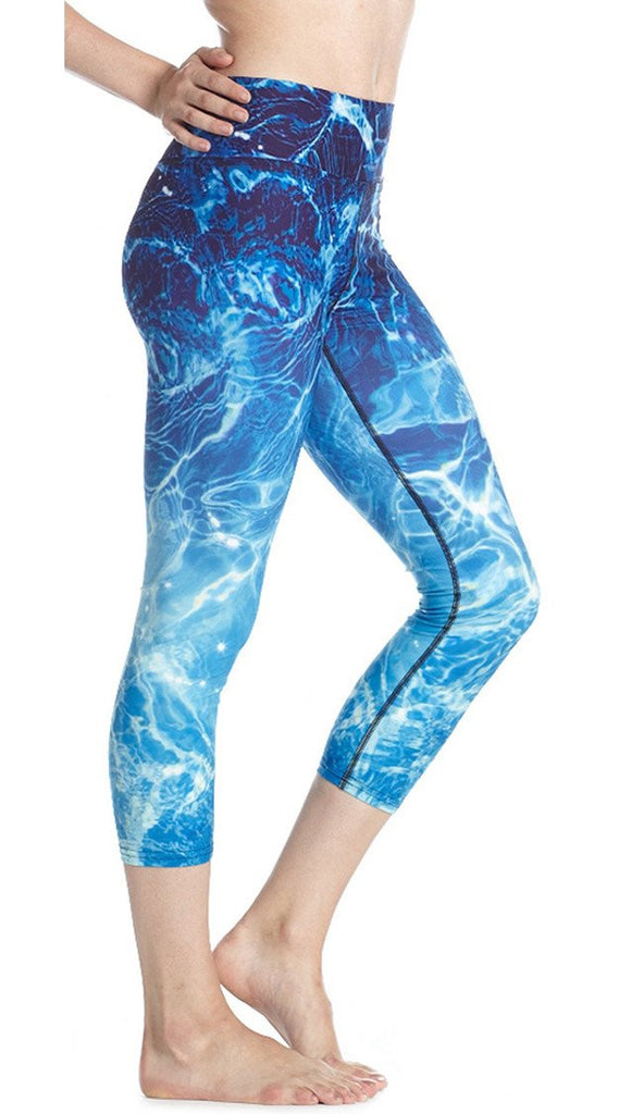 close up side view of model wearing water / ocean themed printed capri leggings