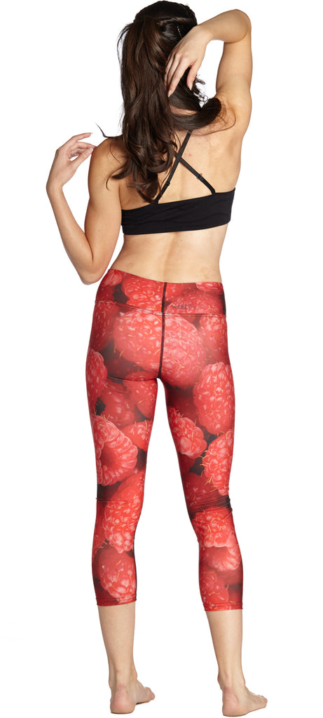 Model wearing WERKSHOP Raspberries Capri Leggings. The leggings are printed with a macro image of raspberries. They are bright red.
