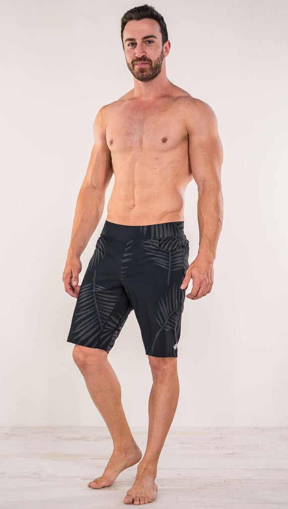 Front view of model wearing tropical palm fronds printed men's performance shorts