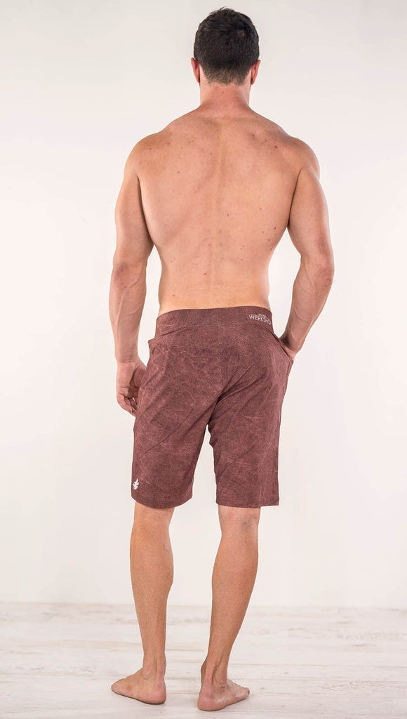 Back view of model wearing brick red printed men's performance shorts