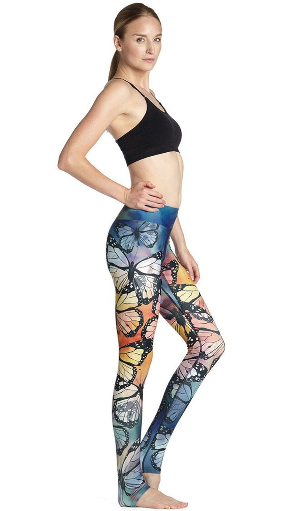 right side view of model wearing colorful butterfly themed printed full length triathlon leggings and matching sports top