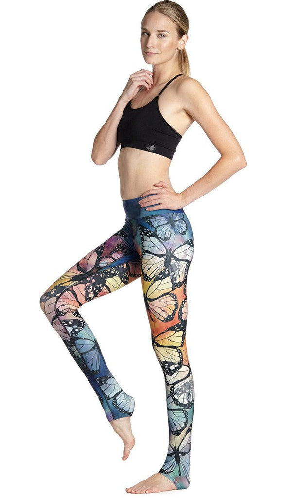 left side view of model wearing colorful butterfly themed printed full length triathlon leggings and sports top
