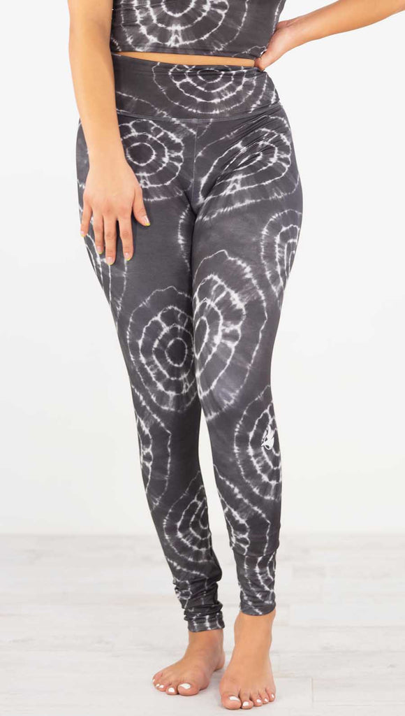 Front view of model wearing the charcoal athleisure leggings. It is in a charcoal color and has white tie dye circles throughout. Each circle has a smaller circle within each other