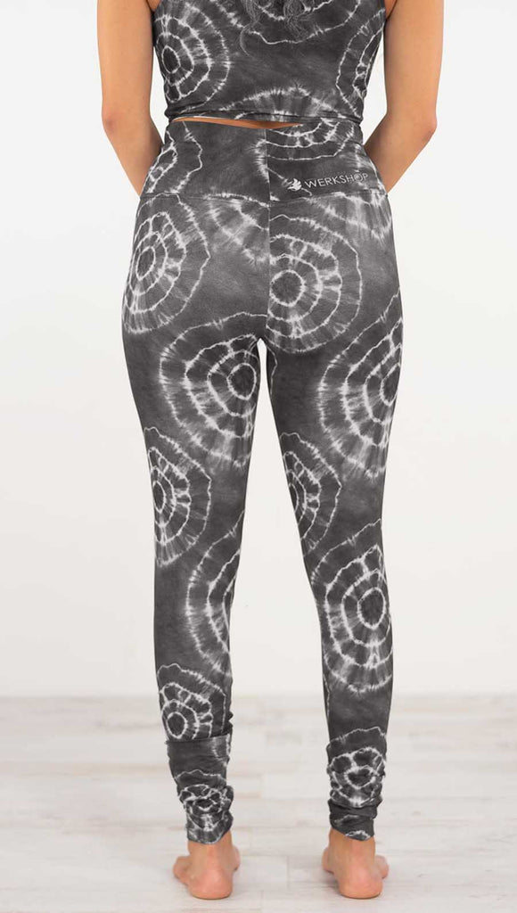 Back view of model wearing the charcoal athleisure leggings. They are in a charcoal color and have white tie dye circles throughout. Each circle has a smaller circle within each other