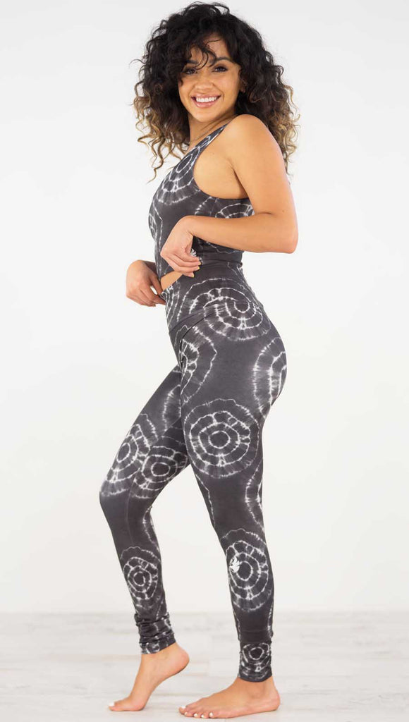 Left side view of model wearing the charcoal athleisure leggings with white tie dye circles throughout. Each circle has a smaller circle within each other.