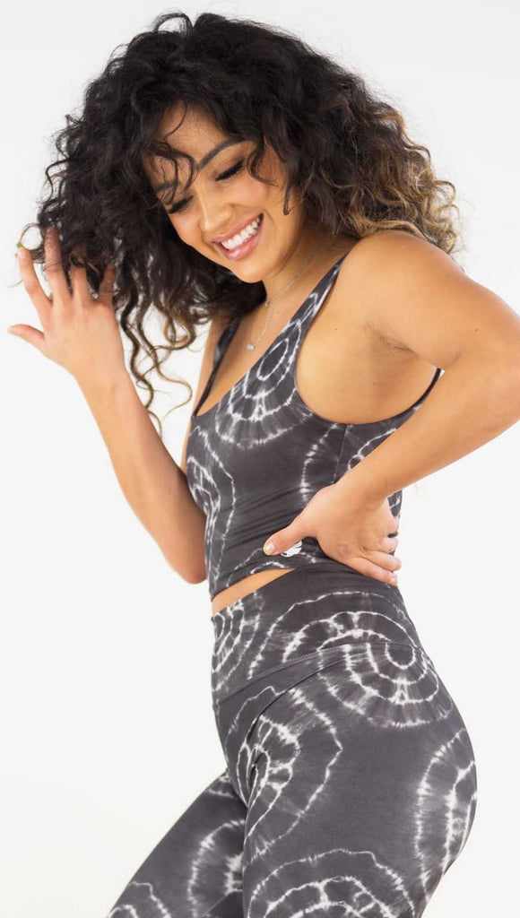Left side view of model wearing the reversible charcoal circles/ spiral crop top. This is the circles side. It is a charcoal color and has white tie dye circles throughout. Each circle has a smaller circle within each other.