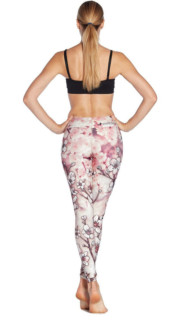 back view of model wearing cherry blossom themed printed full length leggings and sports top