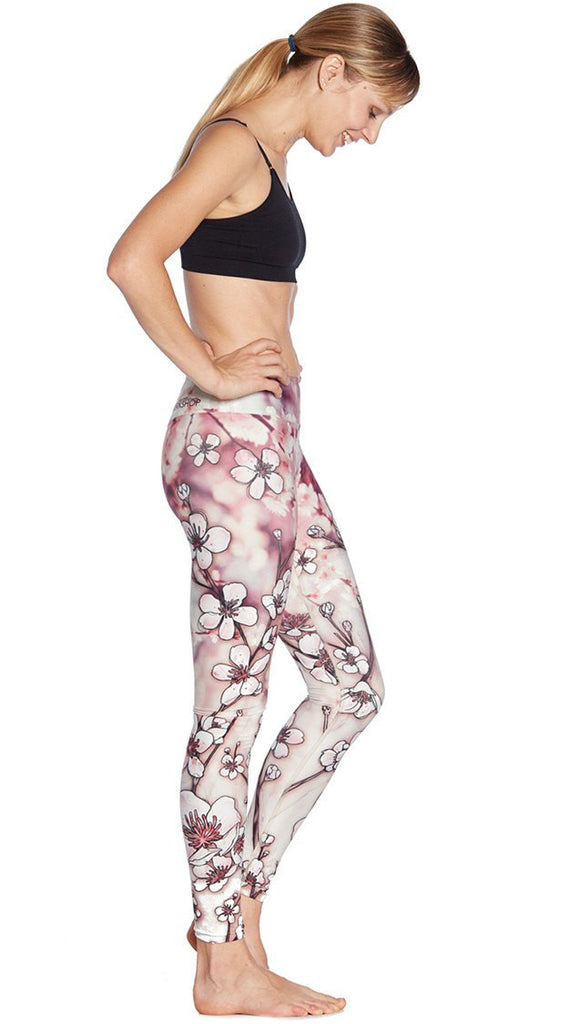 right side view of model wearing cherry blossom themed printed full length leggings and sports top