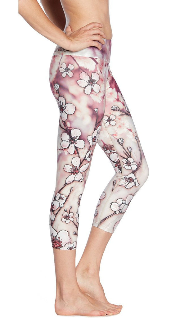 closeup right side view of model wearing cherry blossom themed printed capri leggings