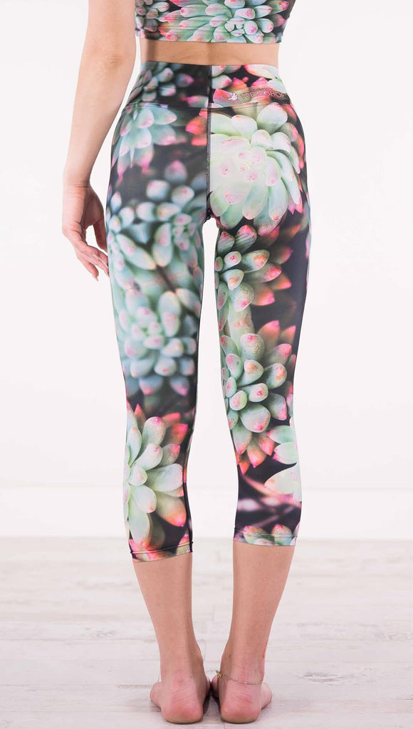 Back view of model wearing black capri leggings with green succulent plants with pink tips throughout
