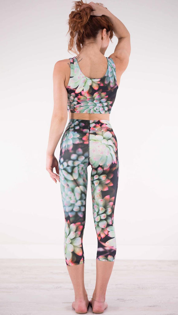 Back view of model wearing black capri leggings with green succulent plants with pink tips throughout