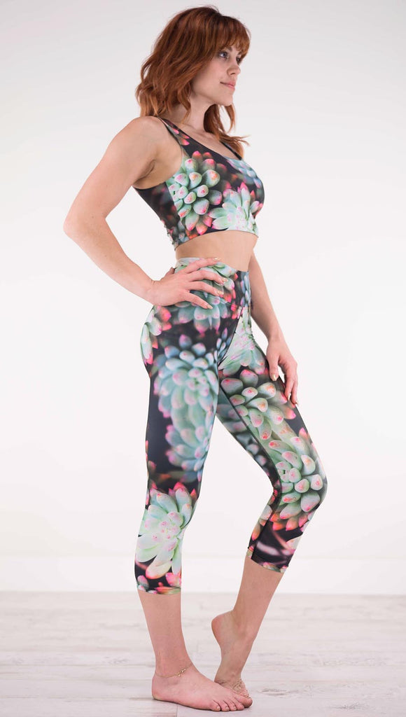 Right view of model wearing black capri leggings with green succulent plants with pink tips throughout and the matching top