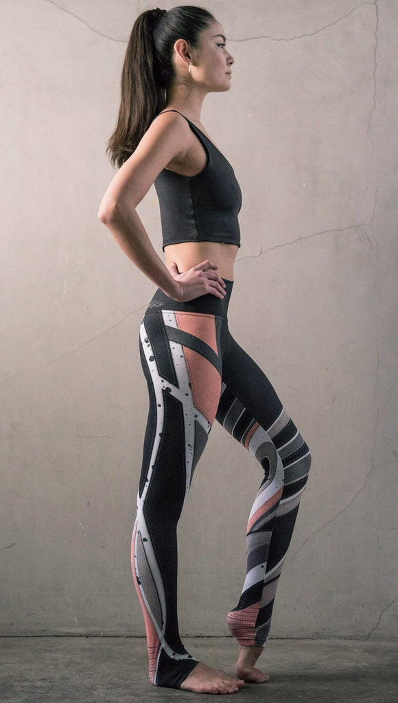 right side view of model wearing striped coral moto themed printed full length leggings