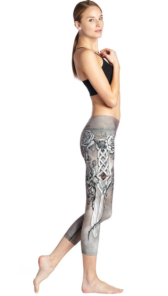 right side view of model wearing sword and roses themed printed capri leggings