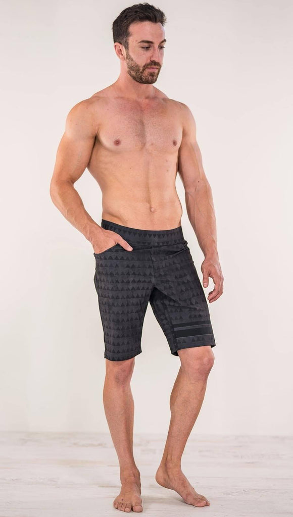 Front view of model wearing charcoal black printed performance shorts with slim fit and distressed tribal inspired art