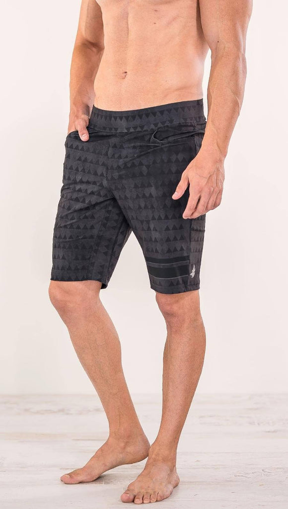 Close up front view of model wearing charcoal black printed performance shorts with slim fit and distressed tribal inspired art