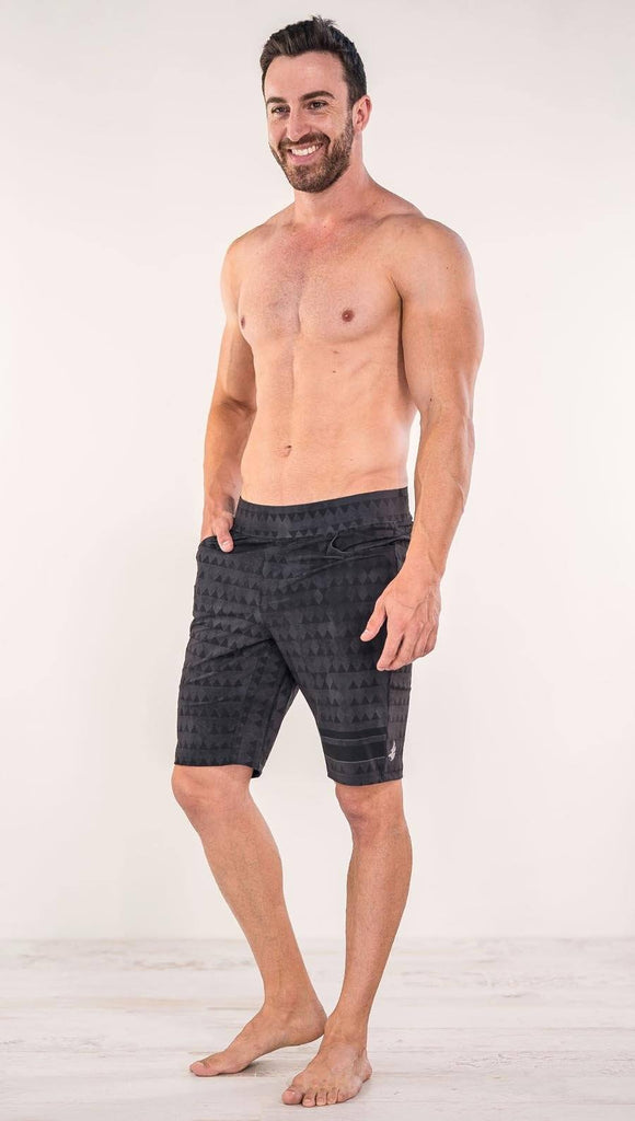 Front view of model wearing charcoal black printed performance shorts with slim fit and distressed tribal inspired art